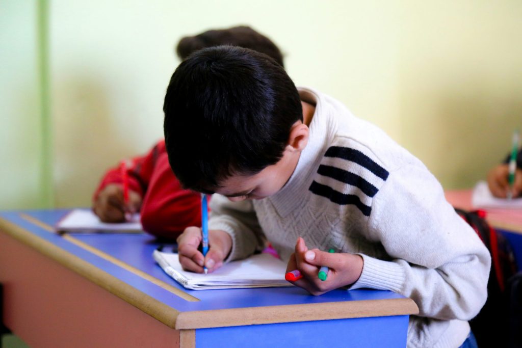 A young boy writing on a piece of paper